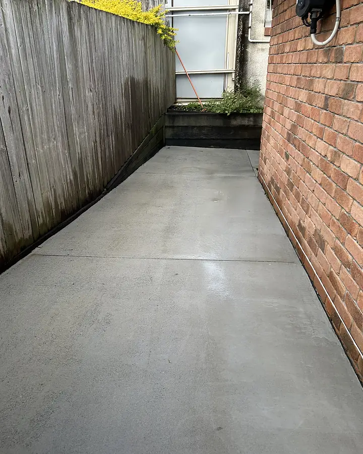 The same concrete side path after pressure cleaning, pale and even