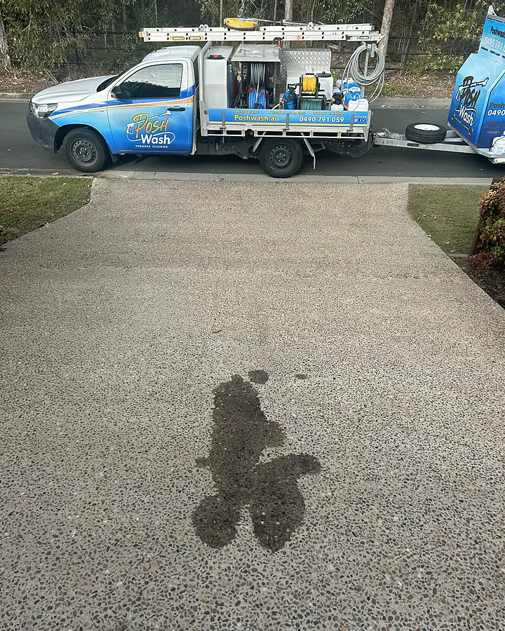 An oil stain soaked into an exposed aggregate driveway before treatment