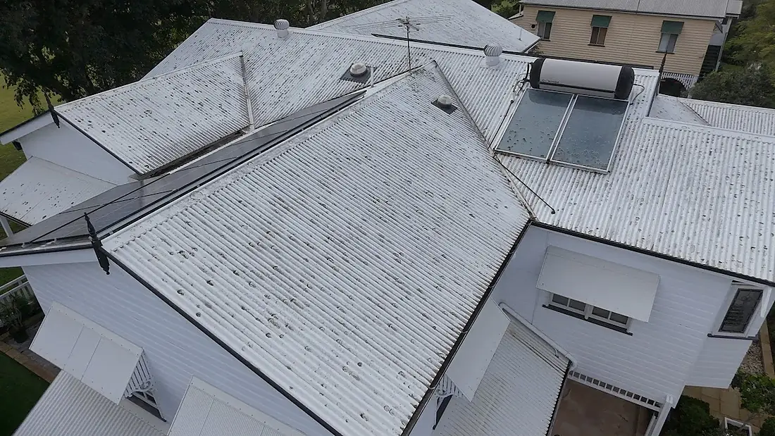 Drone view of a large white Queenslander with a cleaned metal roof