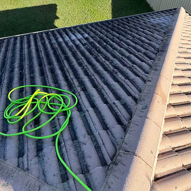 A concrete tile roof dark with mould before roof cleaning