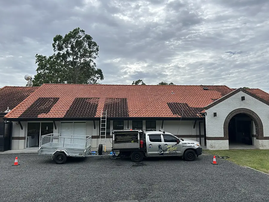 The Posh Wash ute and trailer coned off beside a school building with a soiled tile roof