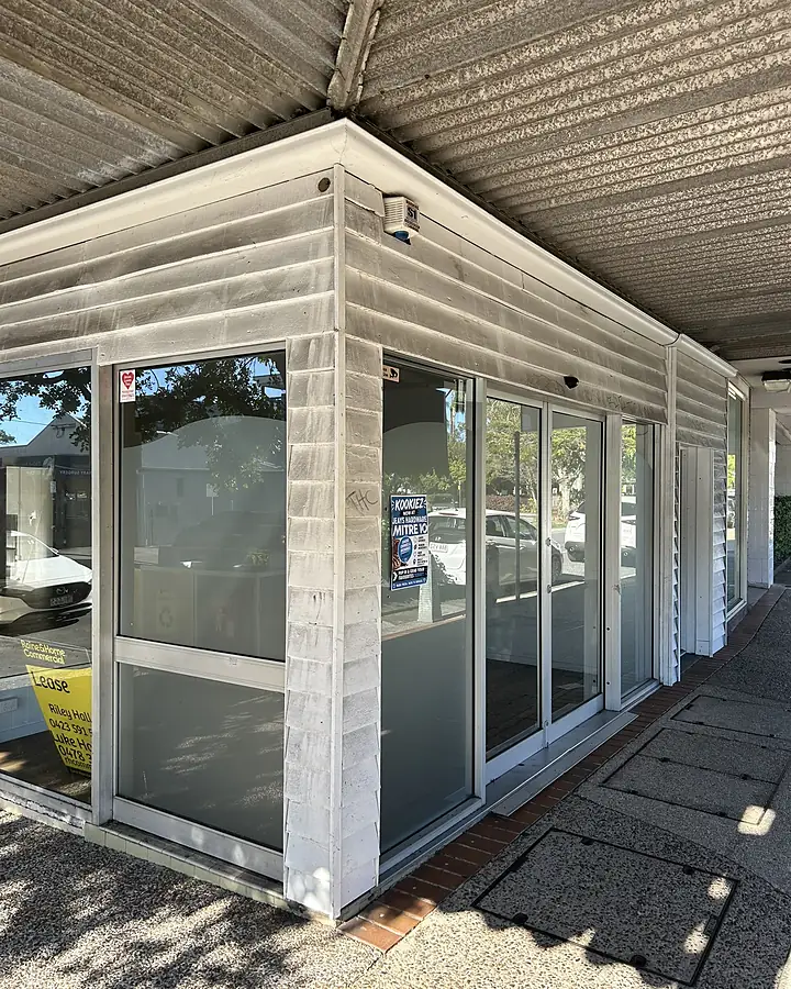 A commercial shopfront entrance with grimy cladding before cleaning