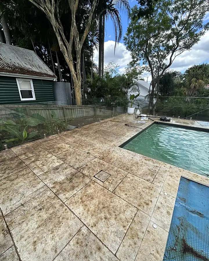 Travertine pool surround with brown staining before cleaning