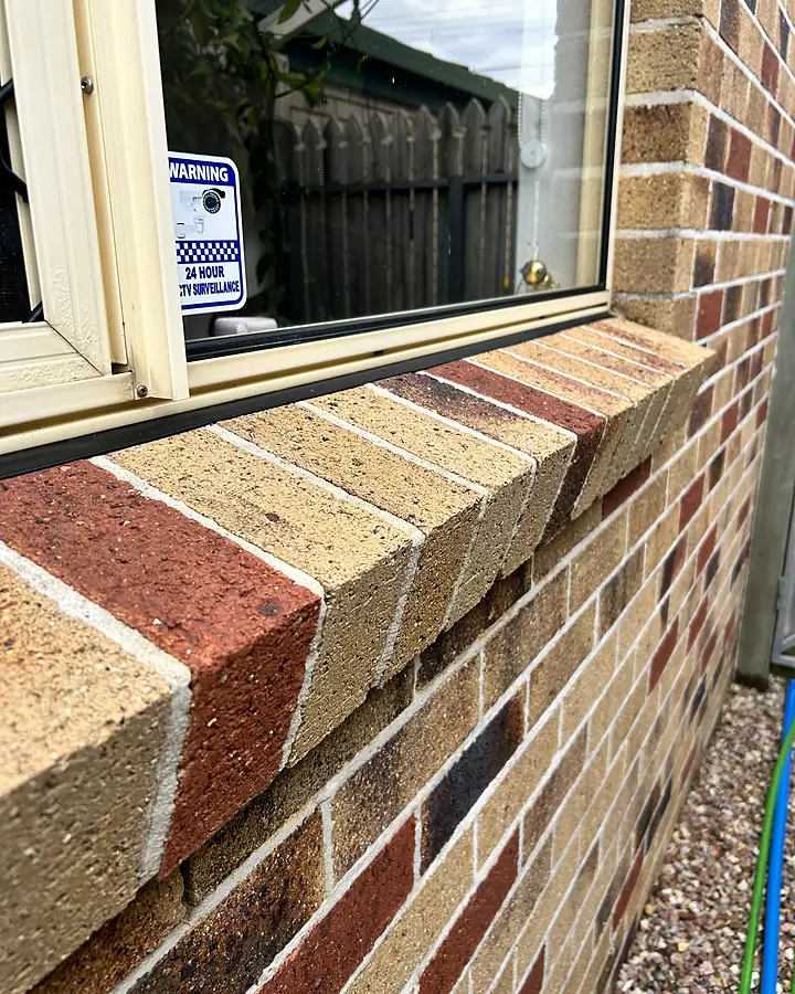 The same window ledge and frame after cleaning, brick colours bright