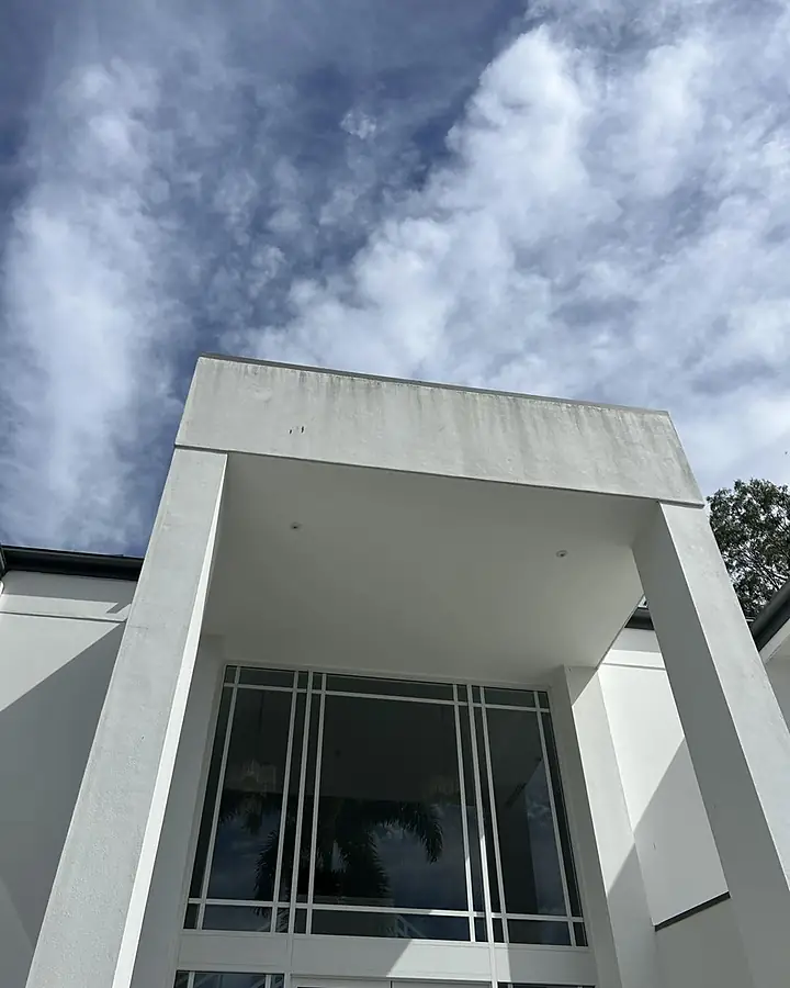 A white rendered portico on a two-storey house streaked with grey mould